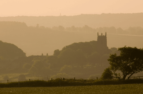 overlooking a church and fields in a spring mist