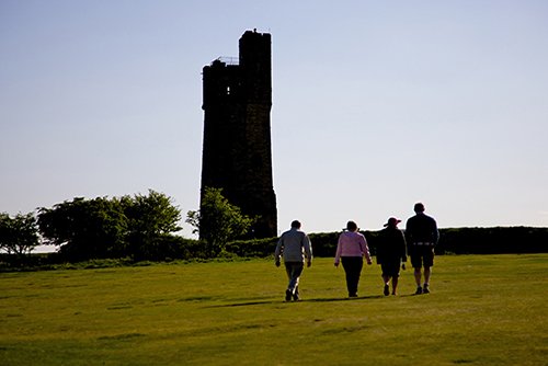 Four people walking towards the Victoria Tower on Castle Hill