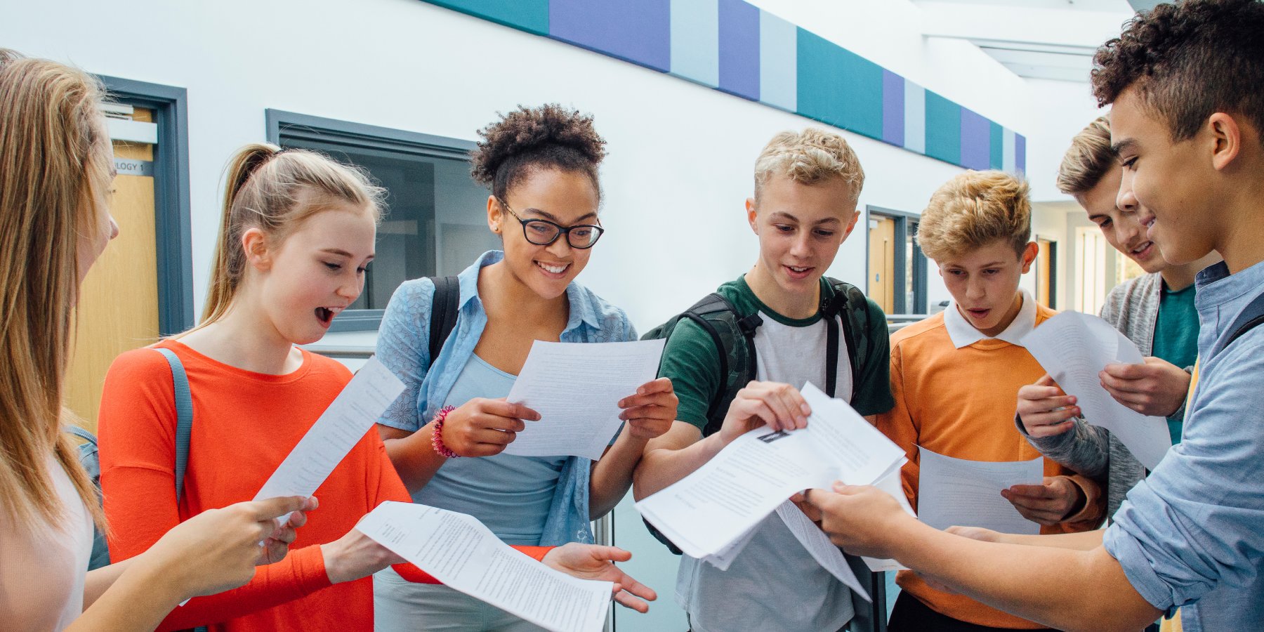 A group of seven students excitedly reading their exam results