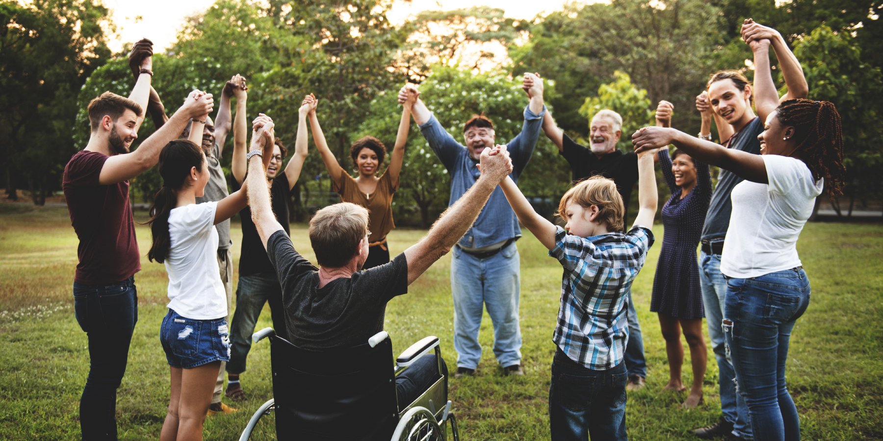 A group of people outside, holding hands in a circle