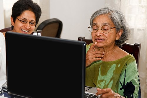 A woman helping an elderly lady on a computer