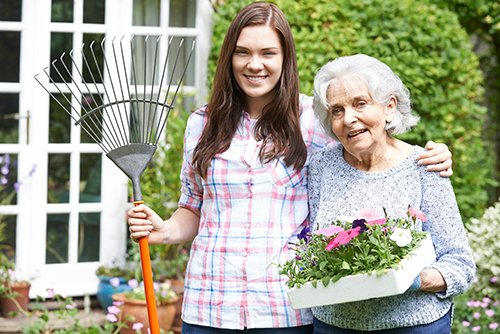 An elderly lady and a young woman gardening together