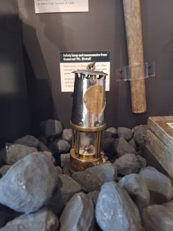 A silver and gold safety lamp from Gomersal Pit on display at Bagshaw Museum.