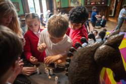 Children playing around a horse statue inside a museum, engaging with the exhibit.