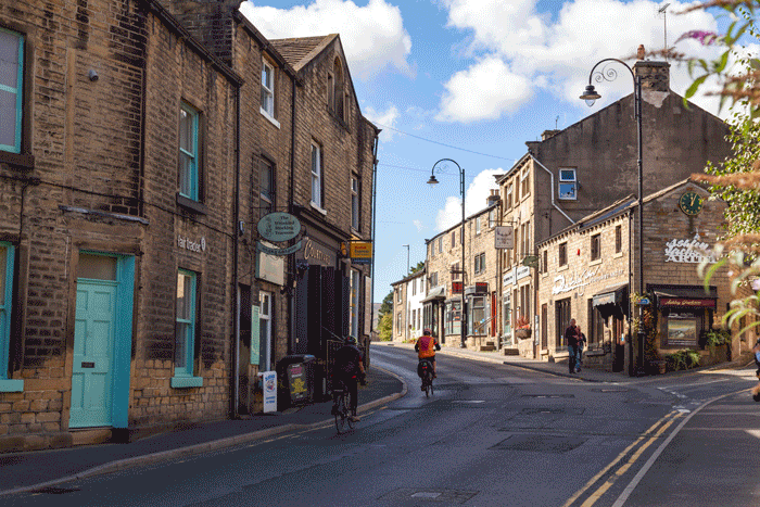 A pretty street in Holmfirth, with narrow pavements and cyclists riding into town