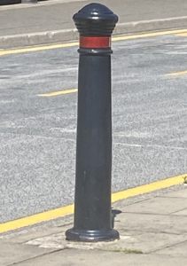 Black metal bollard with a red stripe around the top