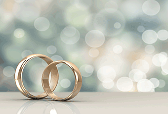 A photo of two gold wedding bands stood up interlinking