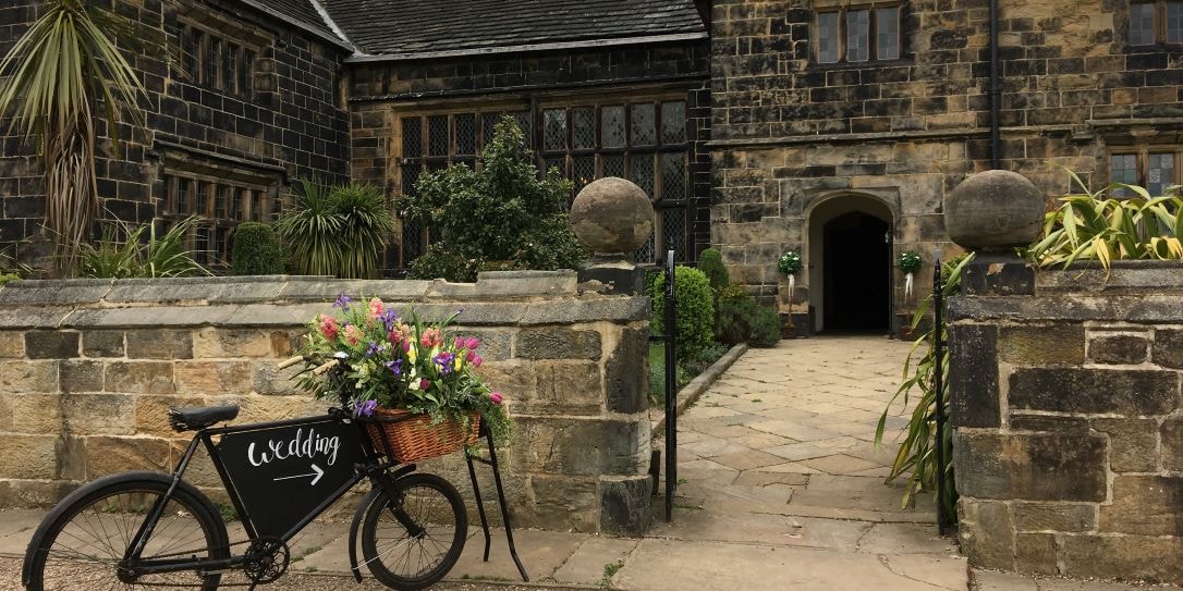 Oakwell Hall entrance with a black bike decorated in floral with 'Weddings' text on it