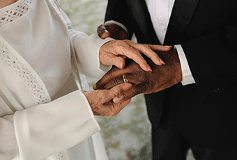 A couple holding hands whilst putting a ring on